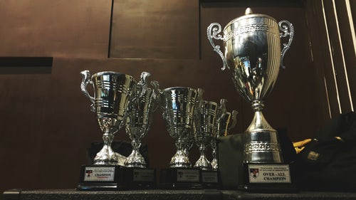 Five golden Karting trophies on a table